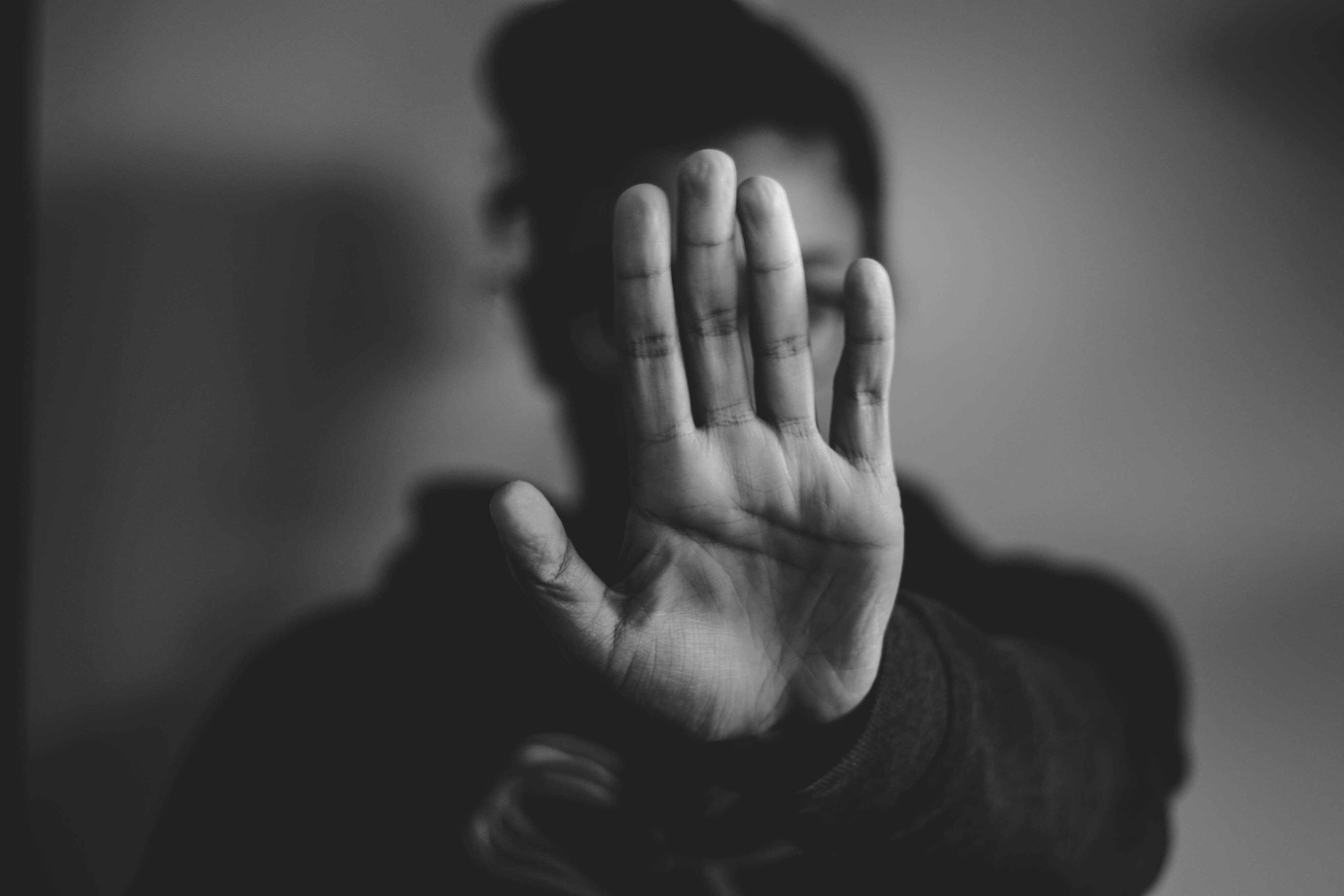 Person holding up their hand protectively, representing how childhood trauma can affect trust, boundaries, and adult relationships.